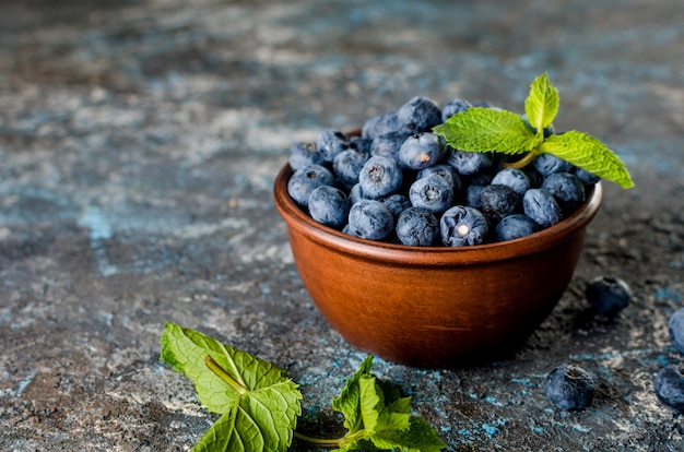 Arándanos maduros en mini bol con hojas de menta