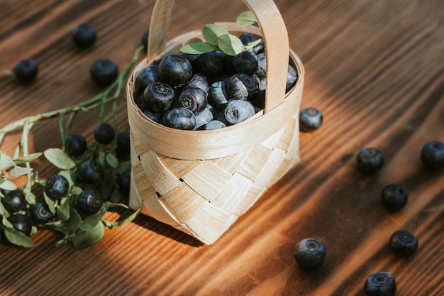 Arándanos en una pequeña cesta de corteza de abedul sobre un fondo de madera. la cosecha de bayas, vitaminas y beneficios para la salud.