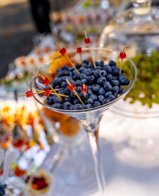 Arándanos en vaso. Pi? Ks de madera en bayas. Catering en boda. Mesa de banquete de bodas. Mesa dulce con frutas, catering para fiestas. Barra de frutas de fiesta.