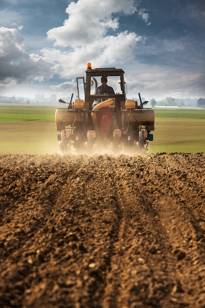 Arar y sembrar campo de maíz con tractor.