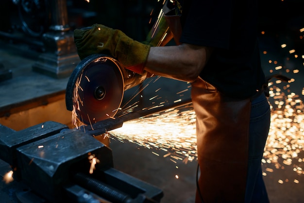 Arbeit an metall. der meister schneidet metall. schleifen der oberfläche mit einer kreissäge. funken fliegen durch starke reibung. arbeit in der garage