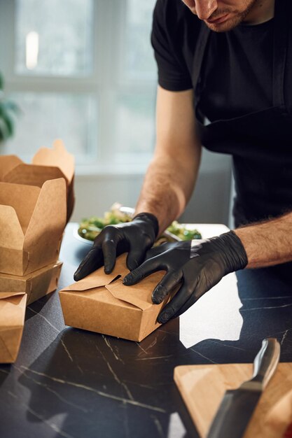 Arbeit in der Küche Mann packt Essen in die Papier-Eko-Kisten Innenraum Restaurant