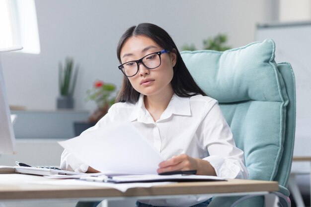 Arbeit mit Dokumenten Porträt einer jungen schönen Geschäftsfrau, mit der der asiatische Buchhalter arbeitet