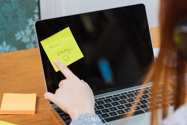 Arbeit von zu Hause aus Konzept, Hände asiatischer junger Frauen, Studentenmädchen zeigen kleines Stück gelbes Papier und schreiben "heute fertig" auf dem Bildschirm Laptop-Computer im Heimbüro