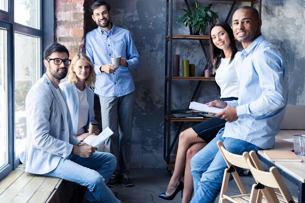 Arbeiten als ein Team. In voller Länge junge moderne Menschen in eleganter Freizeitkleidung, die sich im Kreativbüro treffen