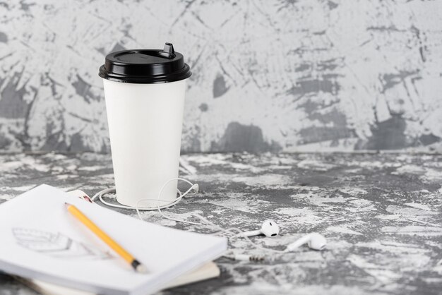 Arbeiten am Los. Kaffeetasse und Notizblock auf grauem Steintisch.