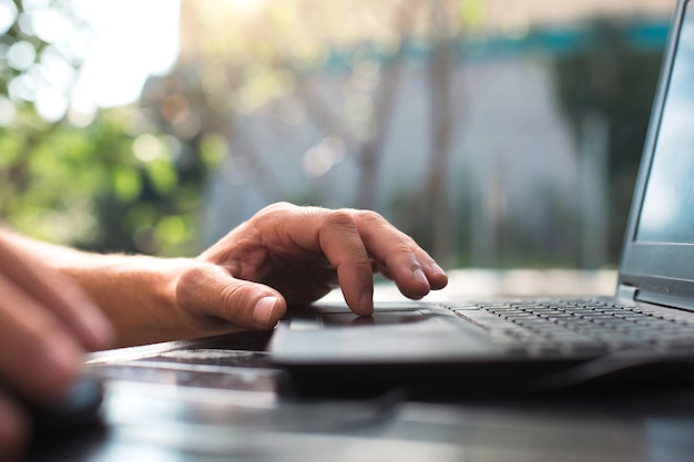 Arbeiten an einem Laptop im Innenhof Männerhände Nahaufnahme Home Office Remote-Arbeit Remote-Standort Verwenden Sie die Tastatur und die Maus, um sich zu entspannen