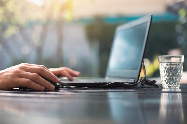 Arbeiten an einem Laptop im Innenhof Männerhände Nahaufnahme Home Office Remote-Arbeit Remote-Standort Verwenden Sie die Tastatur und die Maus, um sich zu entspannen