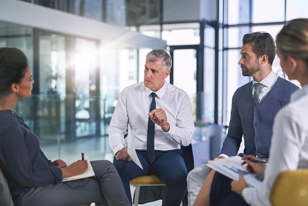 Arbeiten an einem Plan, um ihre Ziele gemeinsam zu erreichen Schnappschuss einer Gruppe von Geschäftsleuten, die in einem Büro diskutieren