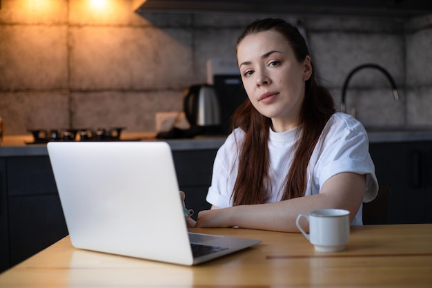 Arbeiten im Küchenbüro Fernarbeit vom Home Office Junge Frau mit Laptop Freelancer-Arbeitsplatz am Küchentisch Fernunterricht