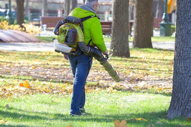 Foto arbeiten im park entfernt blätter mit einem gebläse parkreinigungsdienst entfernen von laub im herbst