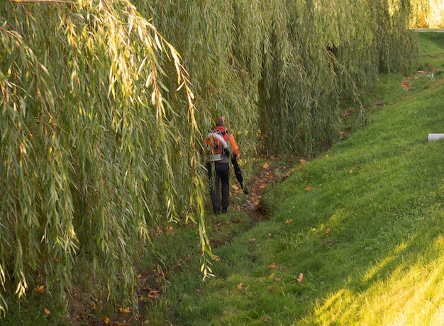 Arbeiten im Park entfernt Herbstlaub mit einem Gebläse