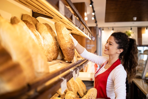 Arbeiten in der Bäckerei, die frisch gebackene Brotlaibe im Regal arrangiert