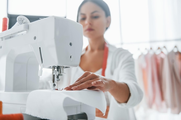 Arbeiten mit der Nähmaschine Die Näherin ist in ihrem Büro mit verschiedenen Kleidungsstücken