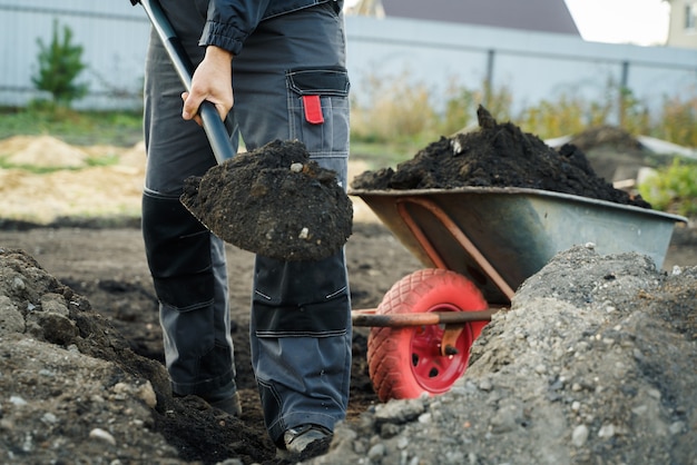 Arbeiten mit Gartengeräte Schaufel und Schubkarre auf dem Gelände eines Landhauses Vorbereitung für