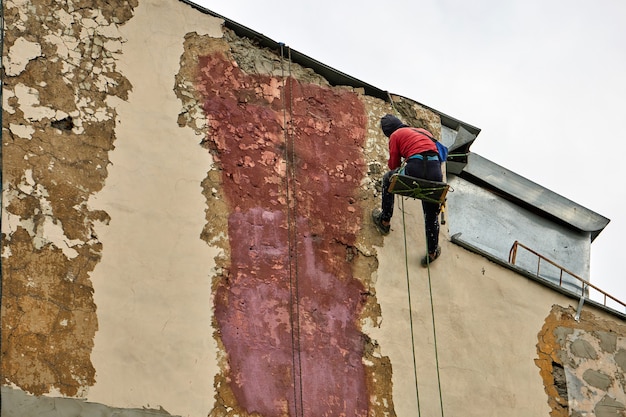 Arbeiten mit Steeplejack mit spezieller Ausrüstung repariert die Fassade des Gebäudes