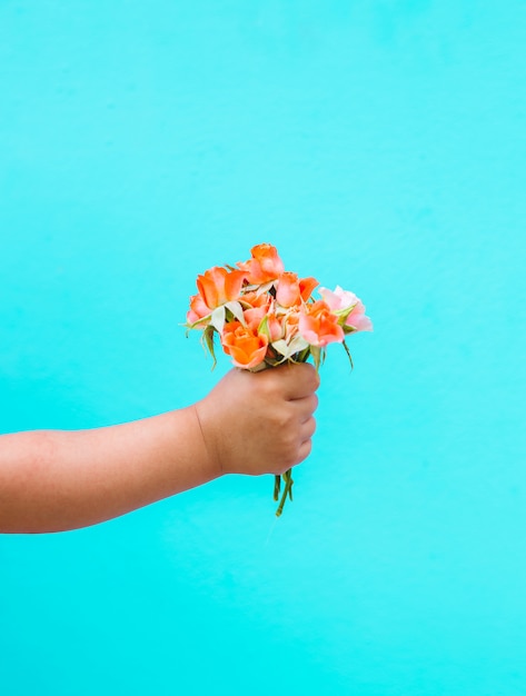 Arbeiten Sie Kunsthand eines kleinen Kindes um, das rosafarbenen Blumenstrauß hält