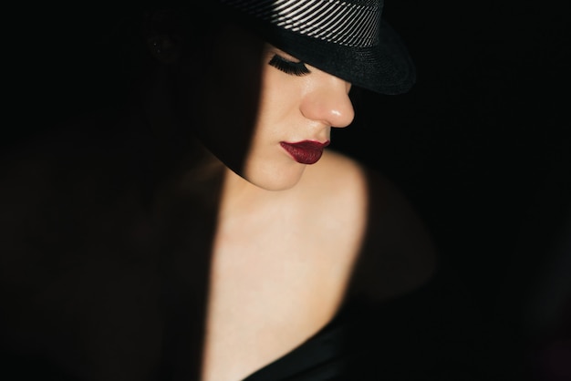 Arbeiten Sie Porträt im Profil eines jungen sexy Mädchens in einem schwarzen Hut mit rotem Lippenstift um