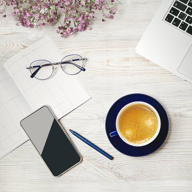 Arbeiten Sie zu Hause Konzept Kaffeetasse mit Laptop Stift Telefon Brille Planung