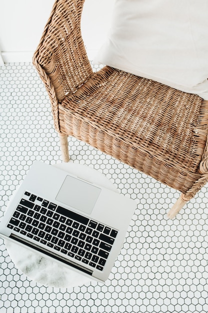 Arbeiten Sie zu Hause Konzept mit Laptop, Rattanstuhl mit Kissen und Marmor Couchtisch auf Balkon mit Mosaikboden