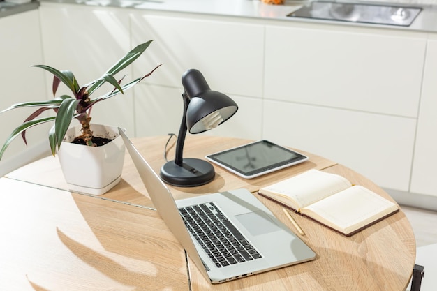 Arbeiten von zu Hause aus - ein Laptop und ein Organizer auf einem Küchentisch mit Küche im Hintergrund.