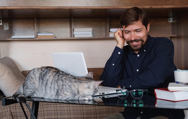 Arbeiten zu Hause mit Haustier auf dem Schoß Der Mensch arbeitet von zu Hause aus und tippt auf dem Laptop