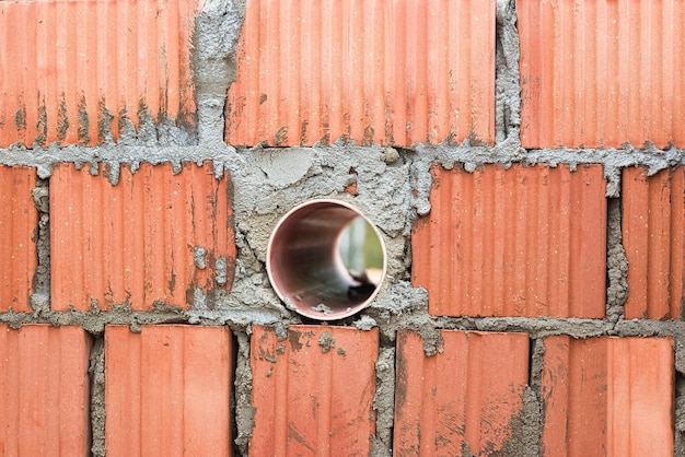 Arbeiten zum Verlegen von Keramikziegeln Rote Backsteinmauer mit Lüftungsloch Eingebettetes Detail in der Wand Progressive Konstruktion von Wänden und Trennwänden