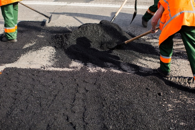 Arbeiter an der Asphaltierfertigermaschine während der Straßenstraßenreparaturarbeiten