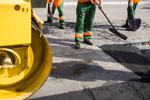Foto arbeiter an der asphaltierfertigermaschine während der straßenstraßenreparaturarbeiten