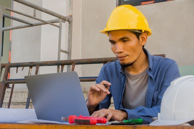 Arbeiter Angestellter, der mit Computertechnologie auf der Baustelle arbeitet