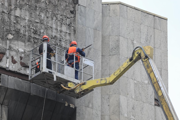 Arbeiter arbeiten an einem Bauaufzug an der Wand eines Gebäudes