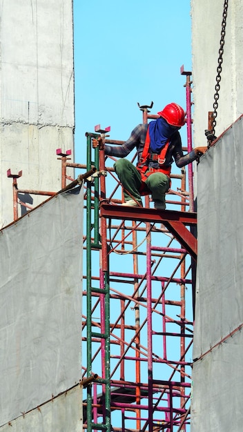 Arbeiter arbeiten auf der Baustelle und setzen Vinyl und Stahl, um das Gebäude und den blauen Himmel zu bedecken.