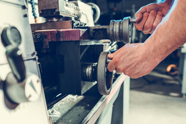 Arbeiter bearbeitet ein Metallstück mit der Drehmaschine aus der Nähe