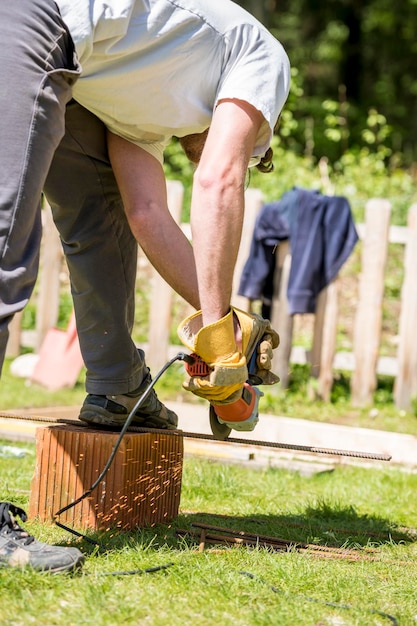 Foto arbeiter beim schneiden von stahlstangen mit einer winkelschleifer-gehrungssäge