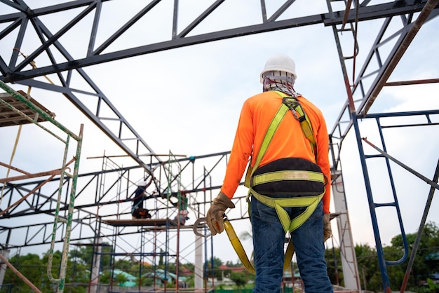 Arbeiter bereiten sich darauf vor, mit einem Fallschutzgerät für Arbeiter mit Haken für Sicherheitsgurte auf der Baustelle aufzusteigen