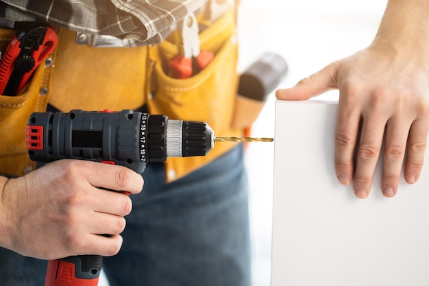 Arbeiter bohren Whiteboard mit mobiler Bohrmaschine im hellen Raum