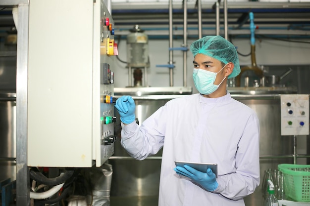 Arbeiter, der die Arbeit der Maschine in der Produktionslinie der Getränkeindustrie kontrolliert