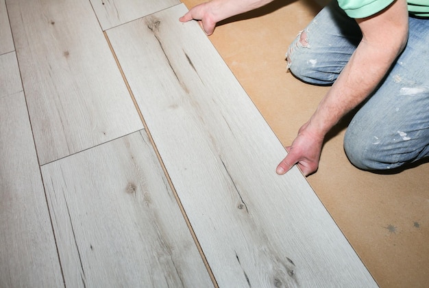 Foto arbeiter, der laminatböden in der wohnung herstellt wartungsreparatur renovierung holzparkettplanken im innenbereich