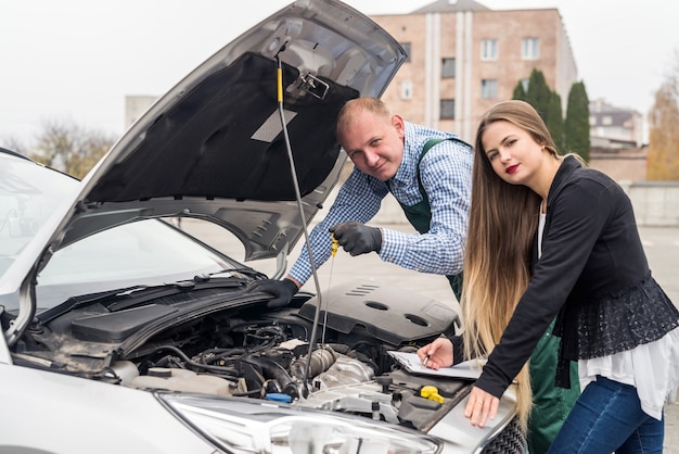 Arbeiter, der Schmiermittelstand prüft und Frau, die in Zwischenablage schreibt