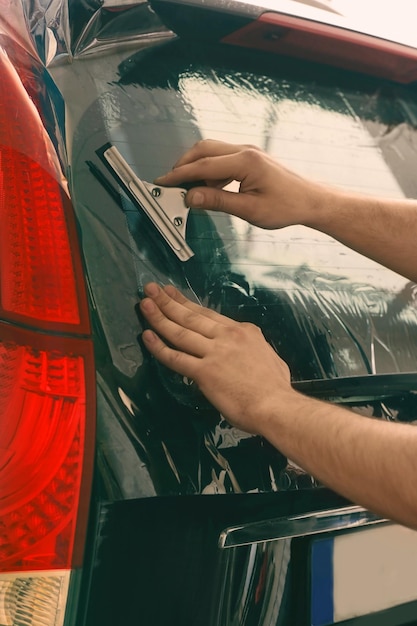 Arbeiter, der Tönungsfolie auf Autofenster aufträgt