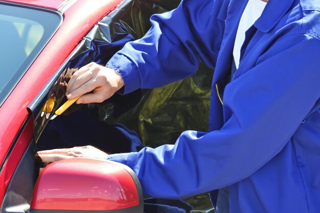 Arbeiter, der Tönungsfolie auf Autofenster aufträgt