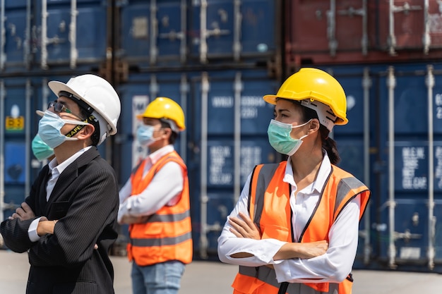 Arbeiter, die eine chirurgische Maske und einen weißen Sicherheitskopf zum Schutz vor Verschmutzung und Viren am Arbeitsplatz tragen