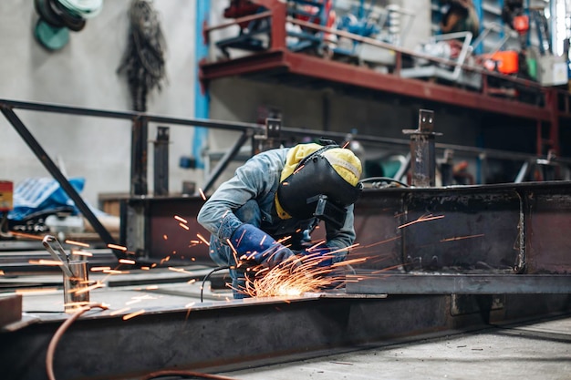 Arbeiter, die elektrisches Funkenschleifen auf Metallstahl verwenden, sind Teil der Balkenstruktur