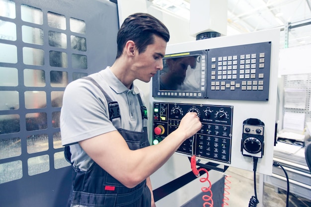 Arbeiter drücken Knöpfe auf CNC-Maschine