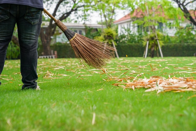 Arbeiter fegt trockene Blätter im Garten