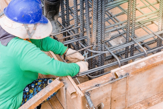 Arbeiter Hände mit Stahldraht und Pinzetten, um Bewehrung zu sichern
