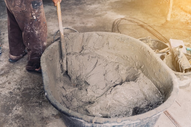 Foto arbeiter hausbauer mischen mörtel aus einem trog im eimer