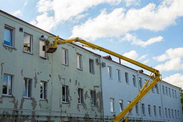 Arbeiter im Korb eines Autoliftes reparieren die Fassade eines Verwaltungsgebäudes