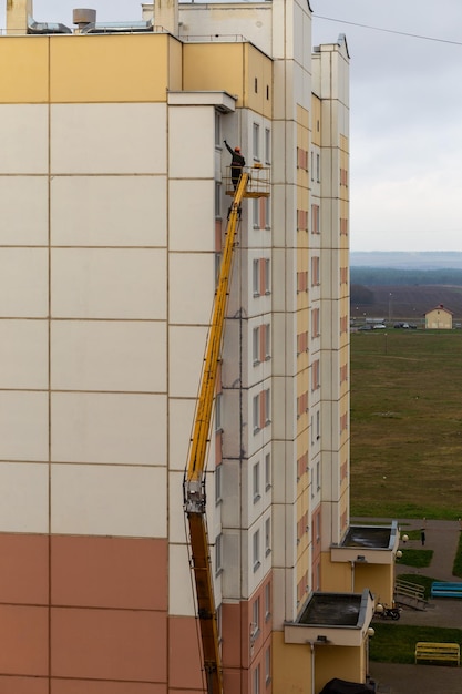 Arbeiter im Korb eines Autolifts reparieren die Fassade eines Wohnhauses