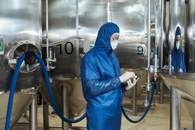 Arbeiter im Schutzanzug, der Geräte in einer Chemiefabrik bedient